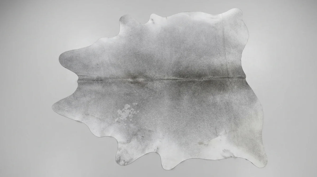 Grey cowhide rug flat lay on white background showing full hide shape