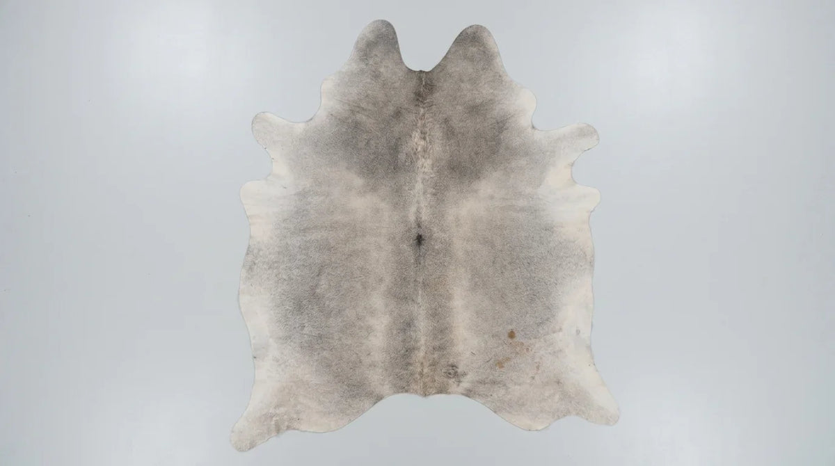 Grey cowhide rug flat lay on white background showing full hide shape