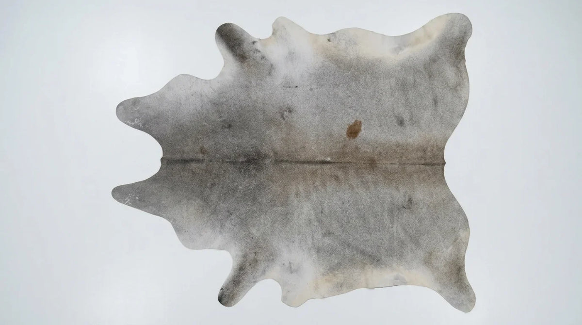 Grey cowhide rug flat lay on white background showing full hide shape