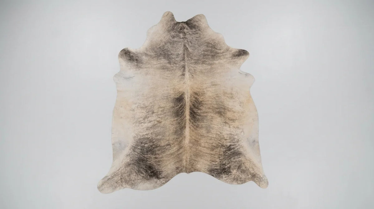Grey cowhide rug flat lay on white background showing full hide shape