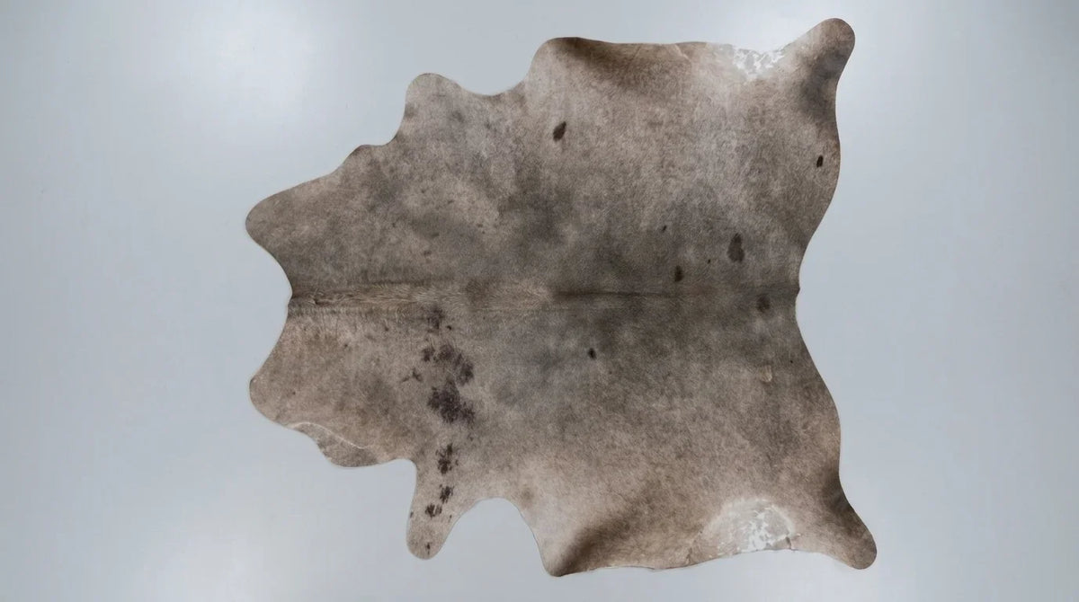 Grey cowhide rug flat lay on white background showing full hide shape