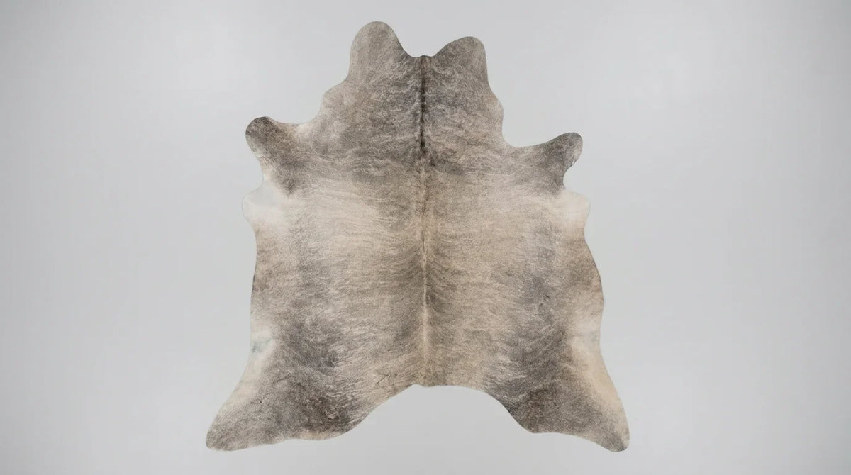 Grey cowhide rug flat lay on white background showing full hide shape