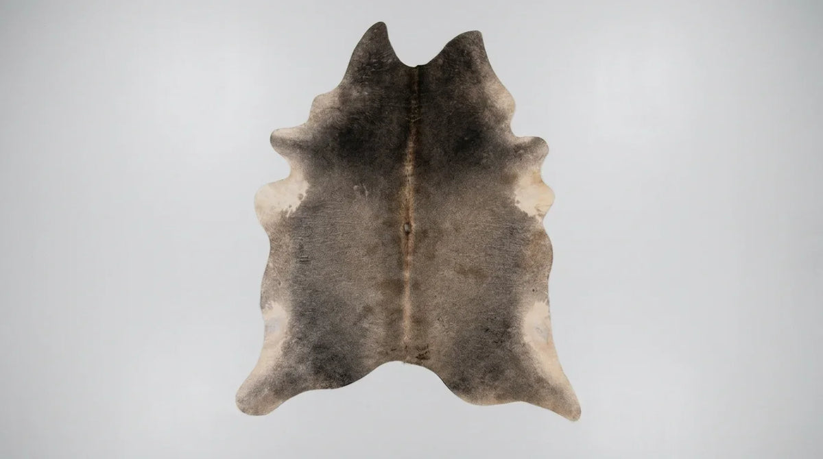 Grey cowhide rug flat lay on white background showing full hide shape
