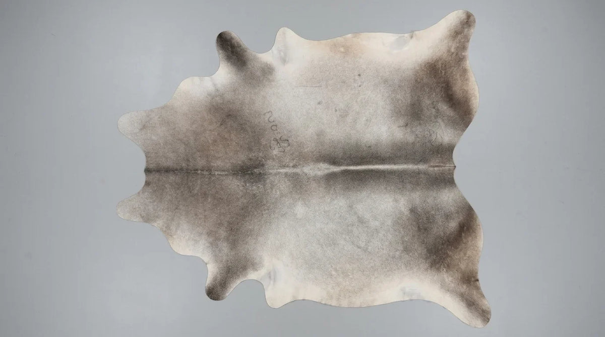 Grey cowhide rug flat lay on white background showing full hide shape
