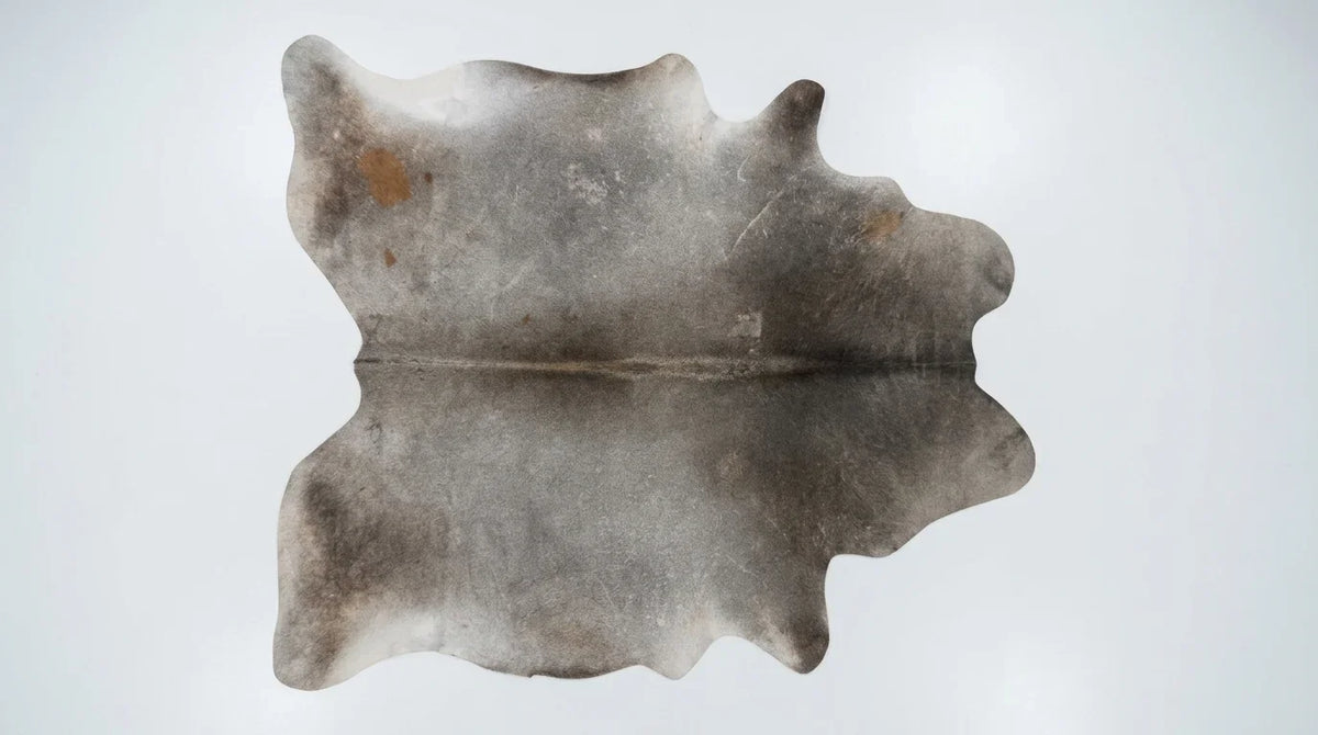 Grey cowhide rug flat lay on white background showing full hide shape