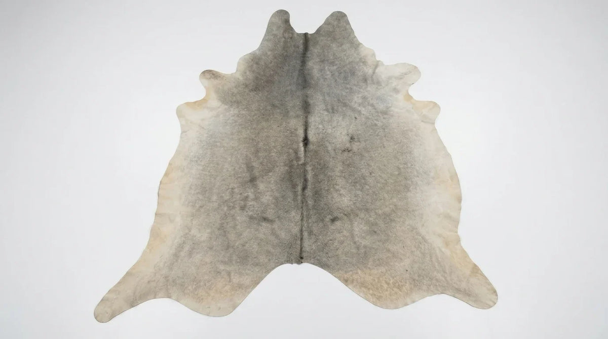 Grey cowhide rug flat lay on white background showing full hide shape