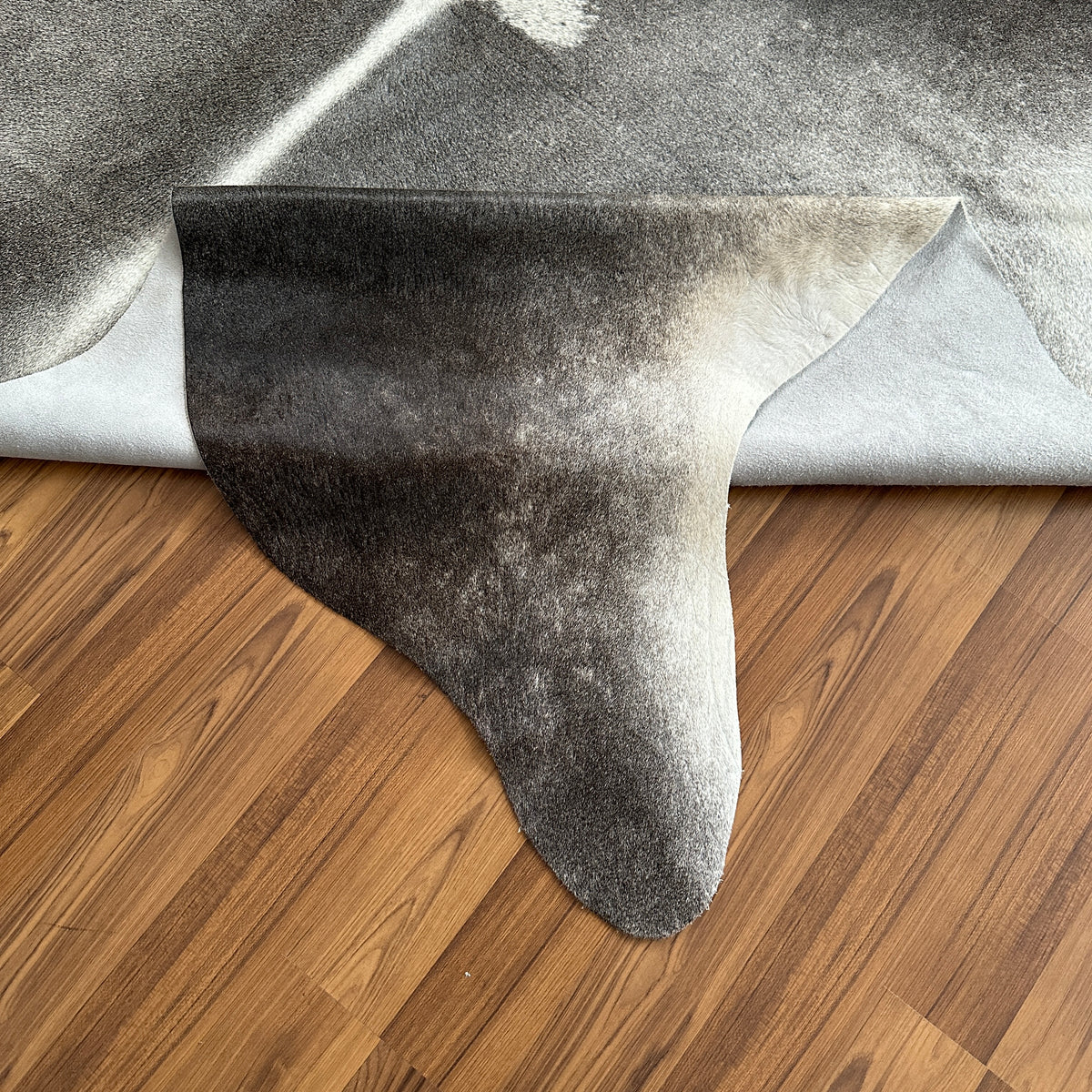 Close-up texture of Grey cowhide rug — Large irregular patches in charcoal and cream tones over a grey base