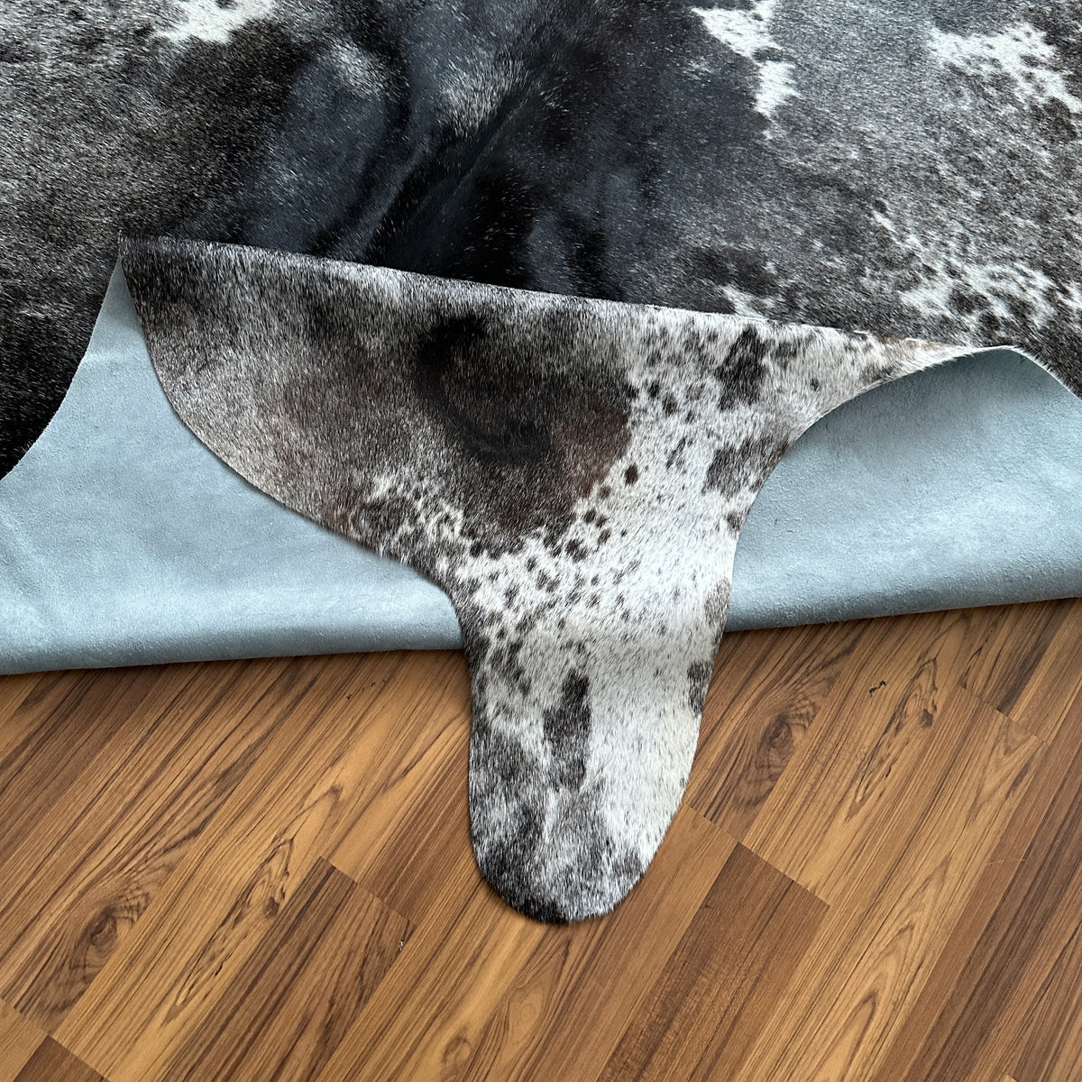 Close-up texture of Grey cowhide rug — Large irregular dark grey and white patches with fine speckled overlay