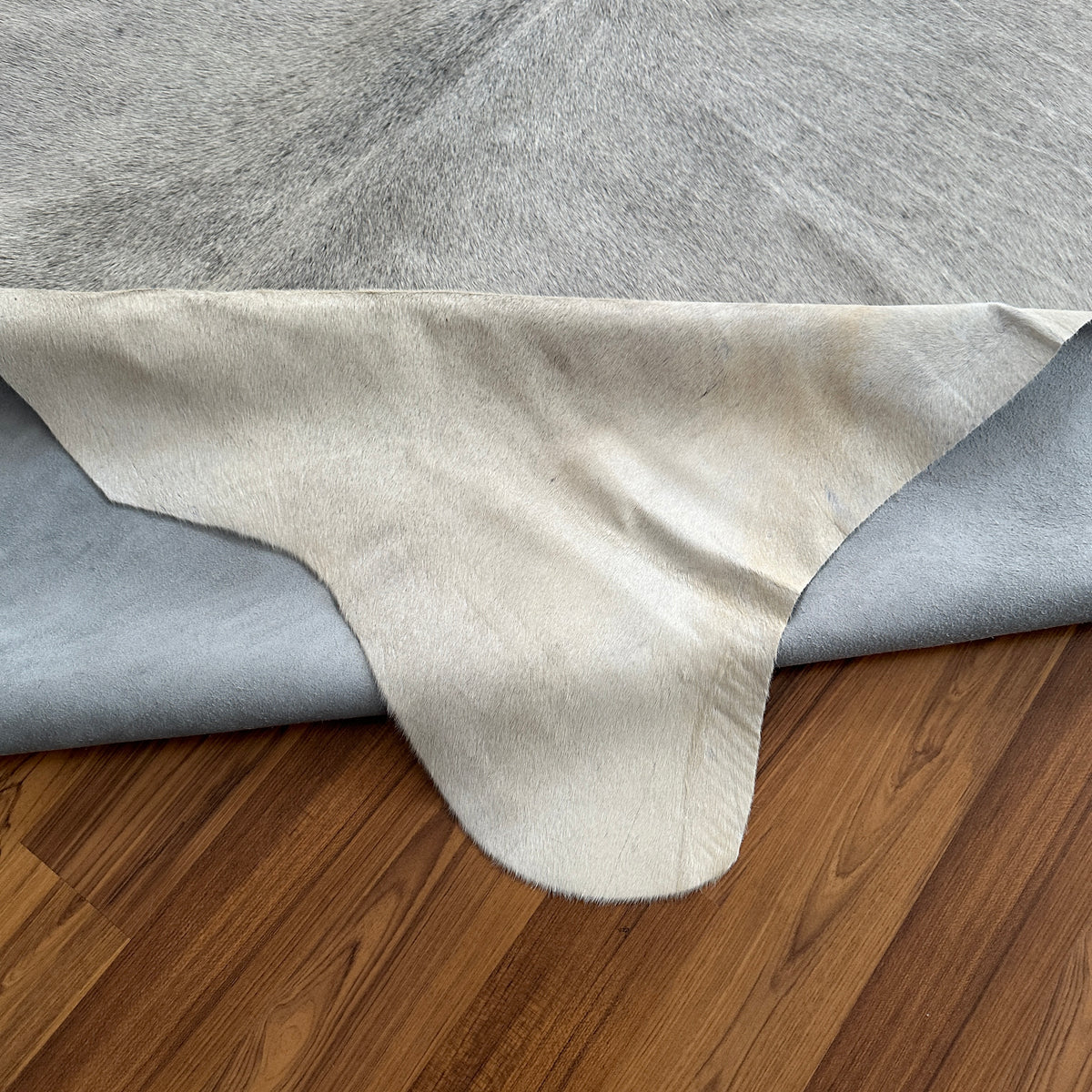 Close-up texture of Grey cowhide rug — Large irregular patches of light grey and cream over a neutral base