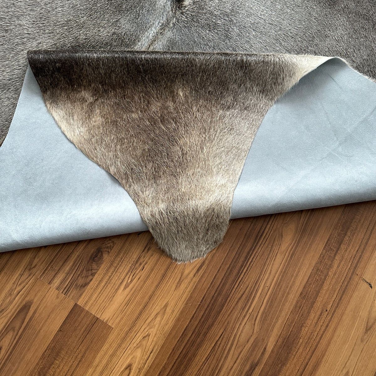 Close-up texture of Grey cowhide rug — Large irregular patches of charcoal and light grey over cream base