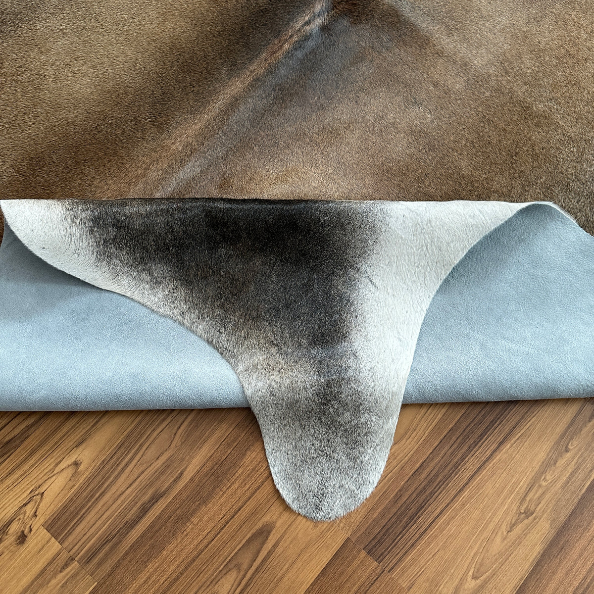 Close-up texture of Grey cowhide rug — Large irregular patches of grey and white with darker undertones across natural hide