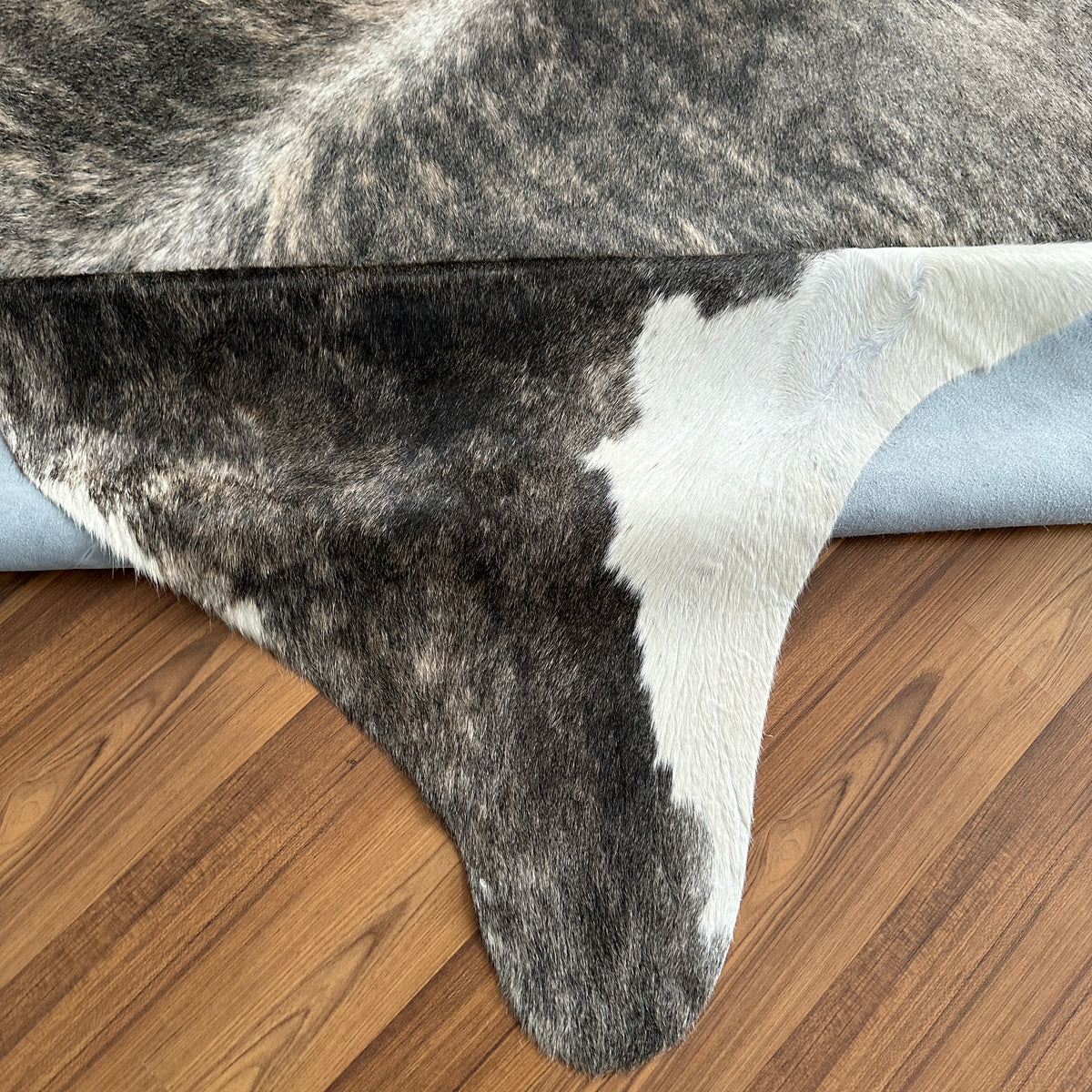 Close-up texture of Grey cowhide rug — Large irregular dark grey and charcoal patches with cream and white accents over light
