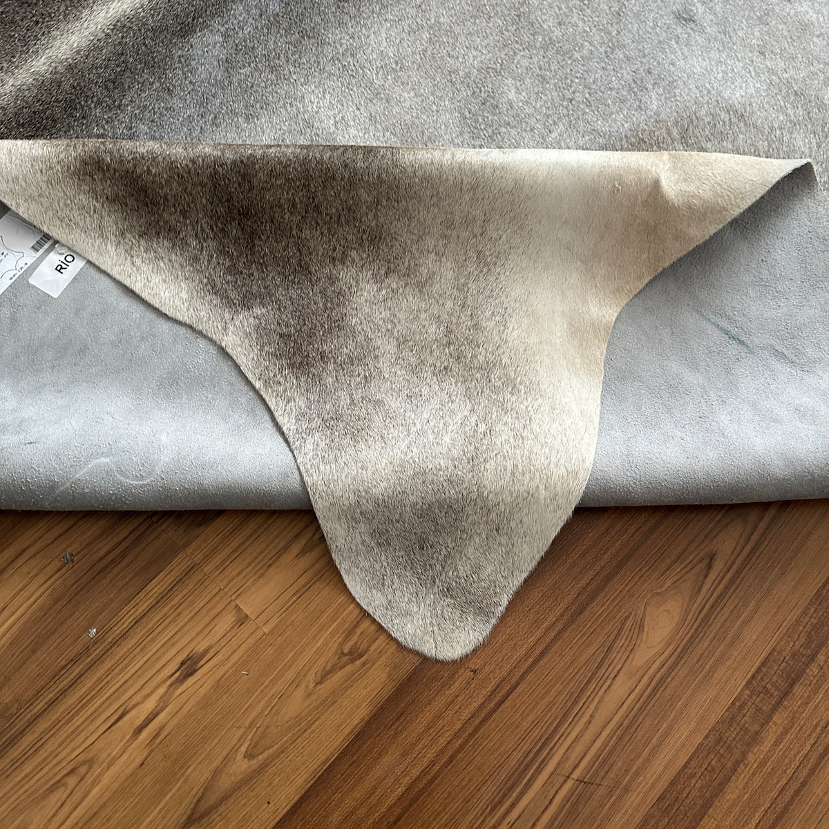 Close-up texture of Grey cowhide rug — Large irregular patches and mottled markings in charcoal and light grey over cream bas