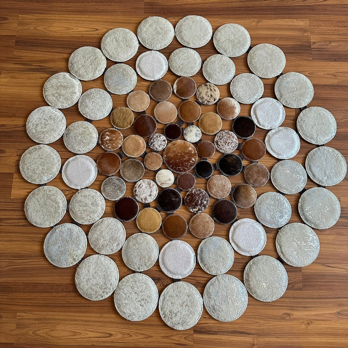 Mixed Tones round patchwork cowhide rug, full overhead view — Small hide discs in cream, beige, tan, and brown tones arranged