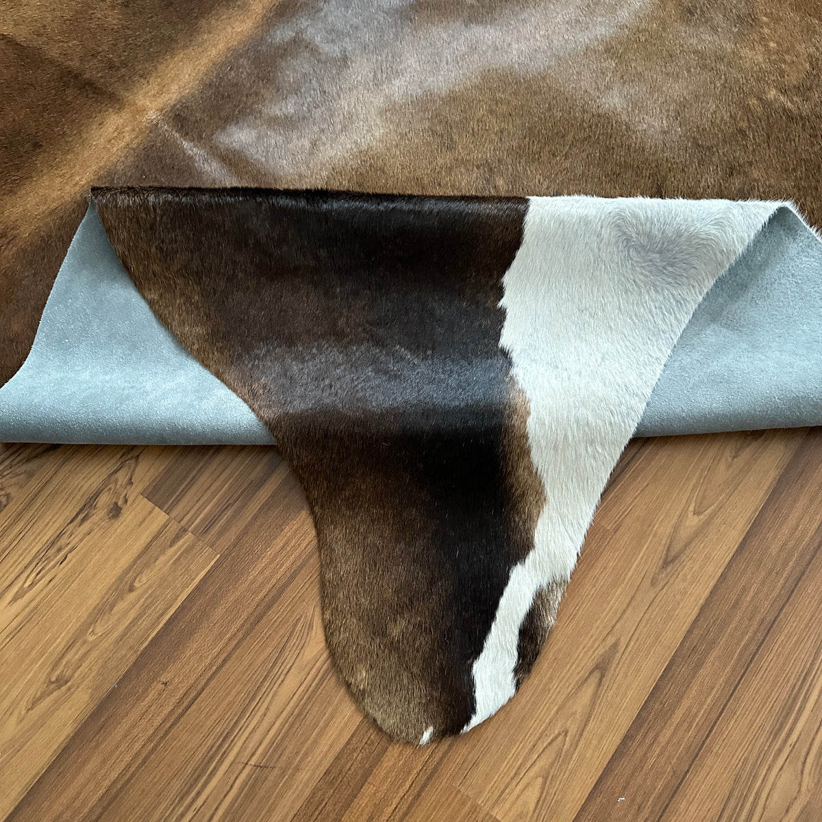 Close-up texture of Tricolor tricolor cowhide rug — Large irregular brown and black patches with cream and white base