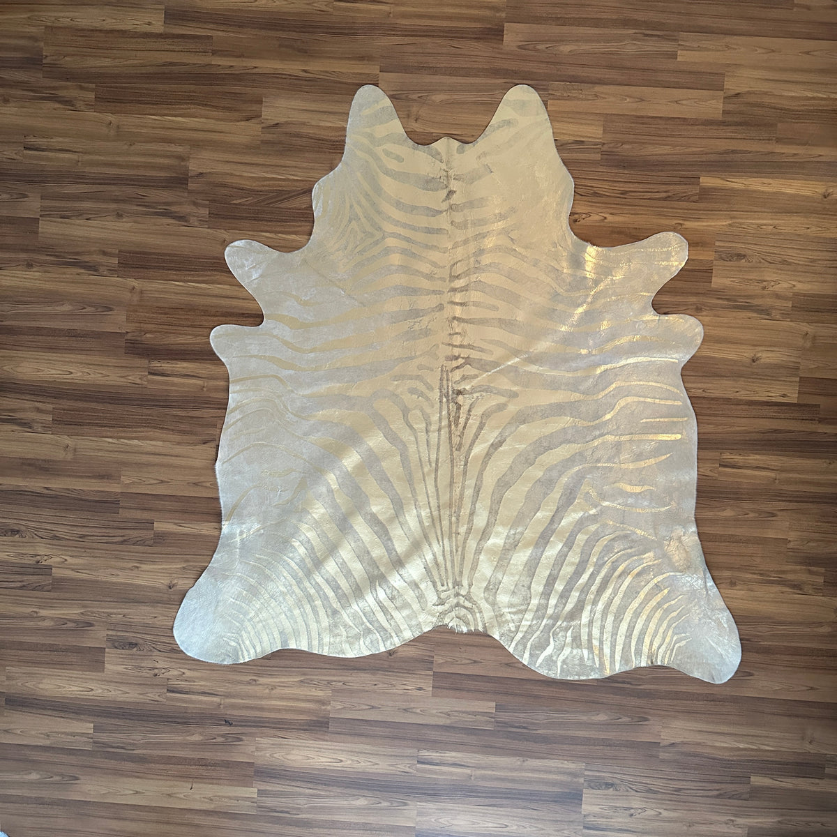Beige and White zebra print cowhide rug, full overhead view — Bold zebra-stripe radiating pattern in grey-brown tones over cr