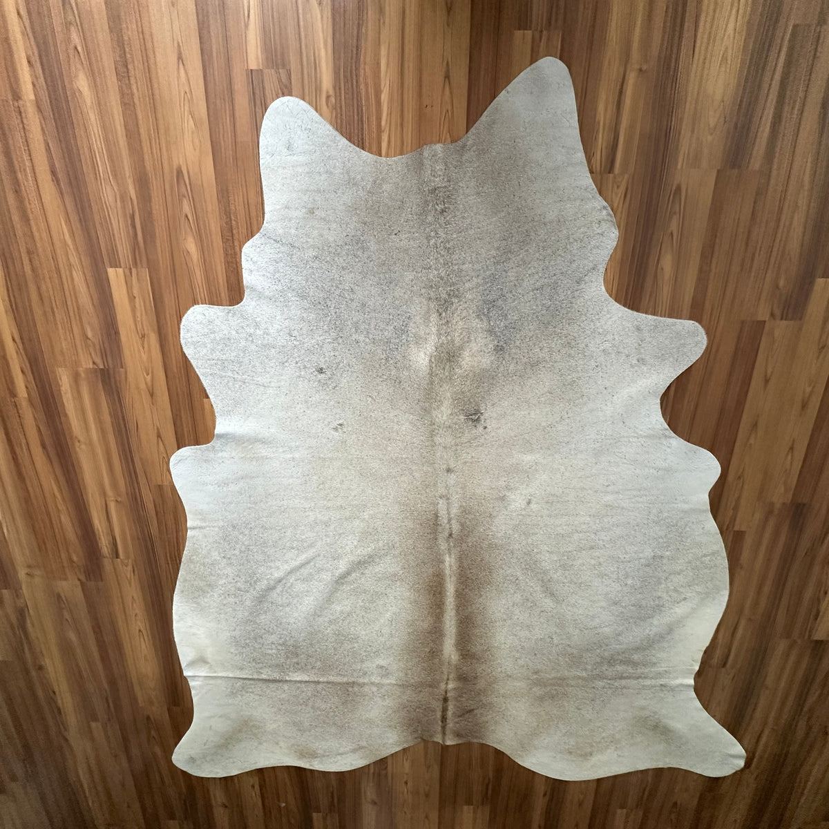 Beige cowhide rug, full overhead view — Subtle natural markings and grain texture over cream base
