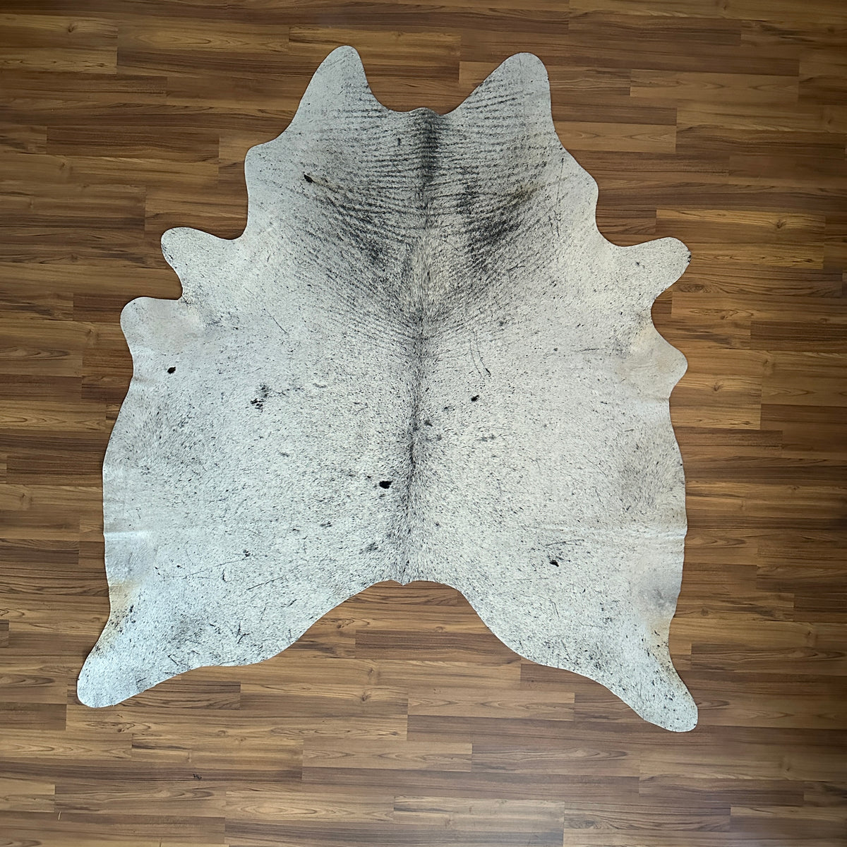 Beige cowhide rug, full overhead view — Fine speckled texture with subtle grey and brown undertones throughout cream base