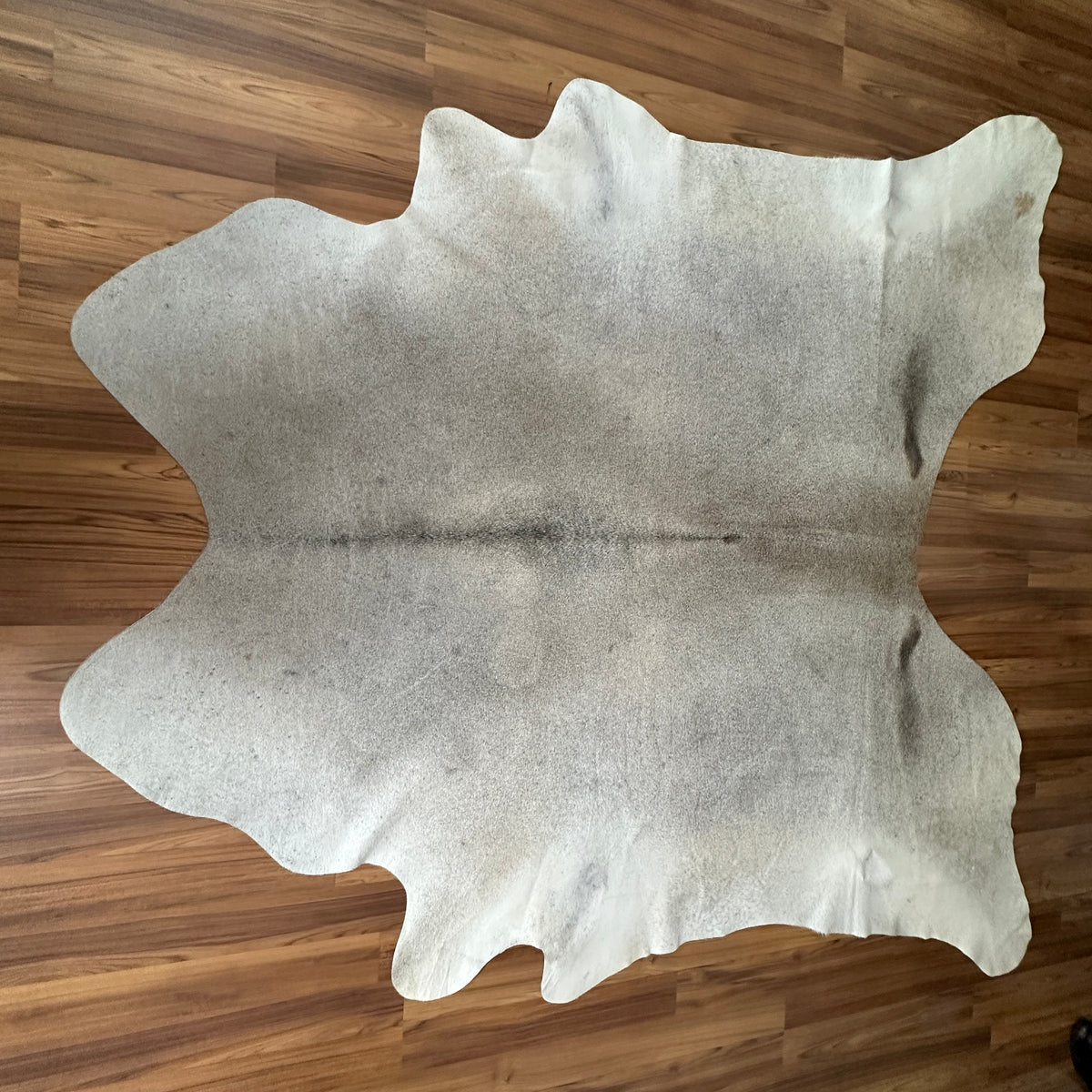 Beige cowhide rug, full overhead view — Soft cream base with light gray-brown undertones and natural irregular markings
