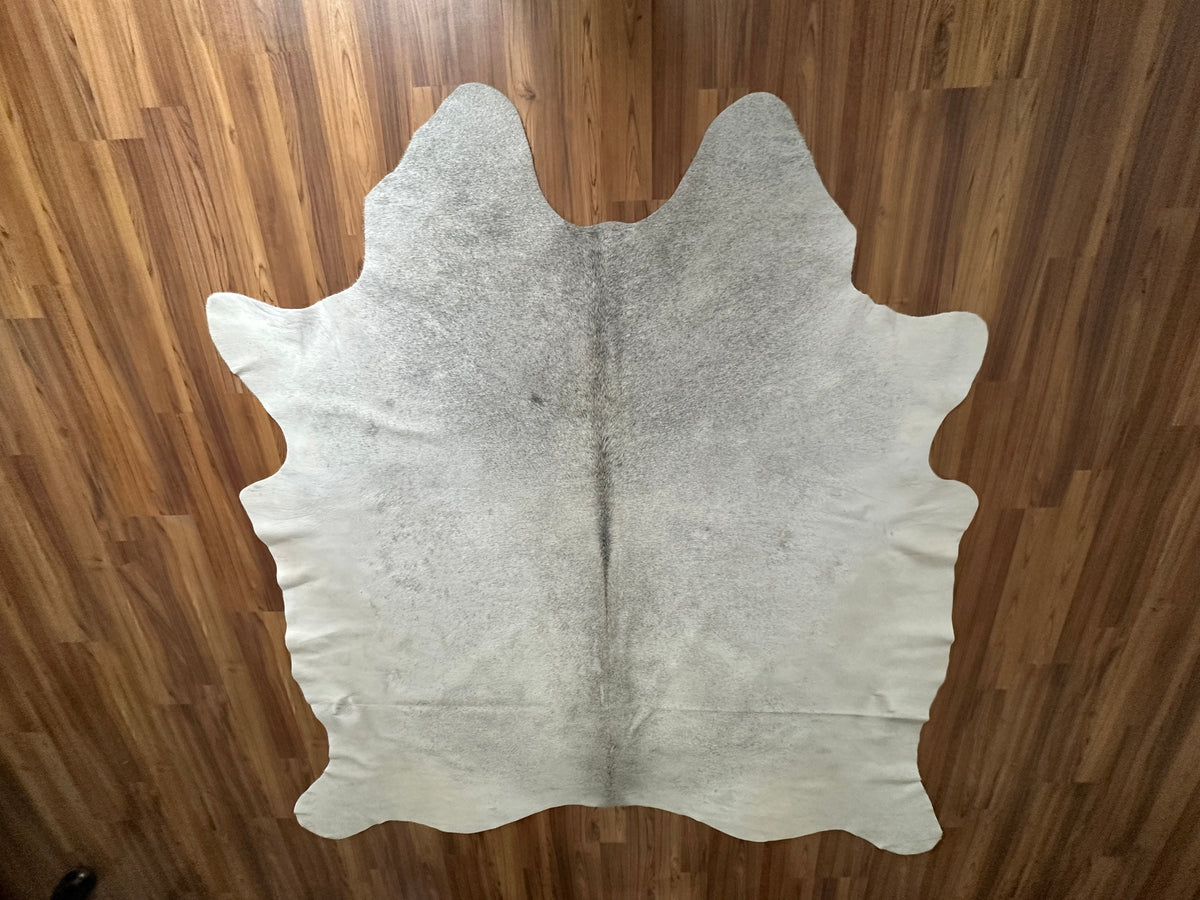 Beige cowhide rug, full overhead view — Cream base with subtle gray-beige tonal variations and natural hide markings