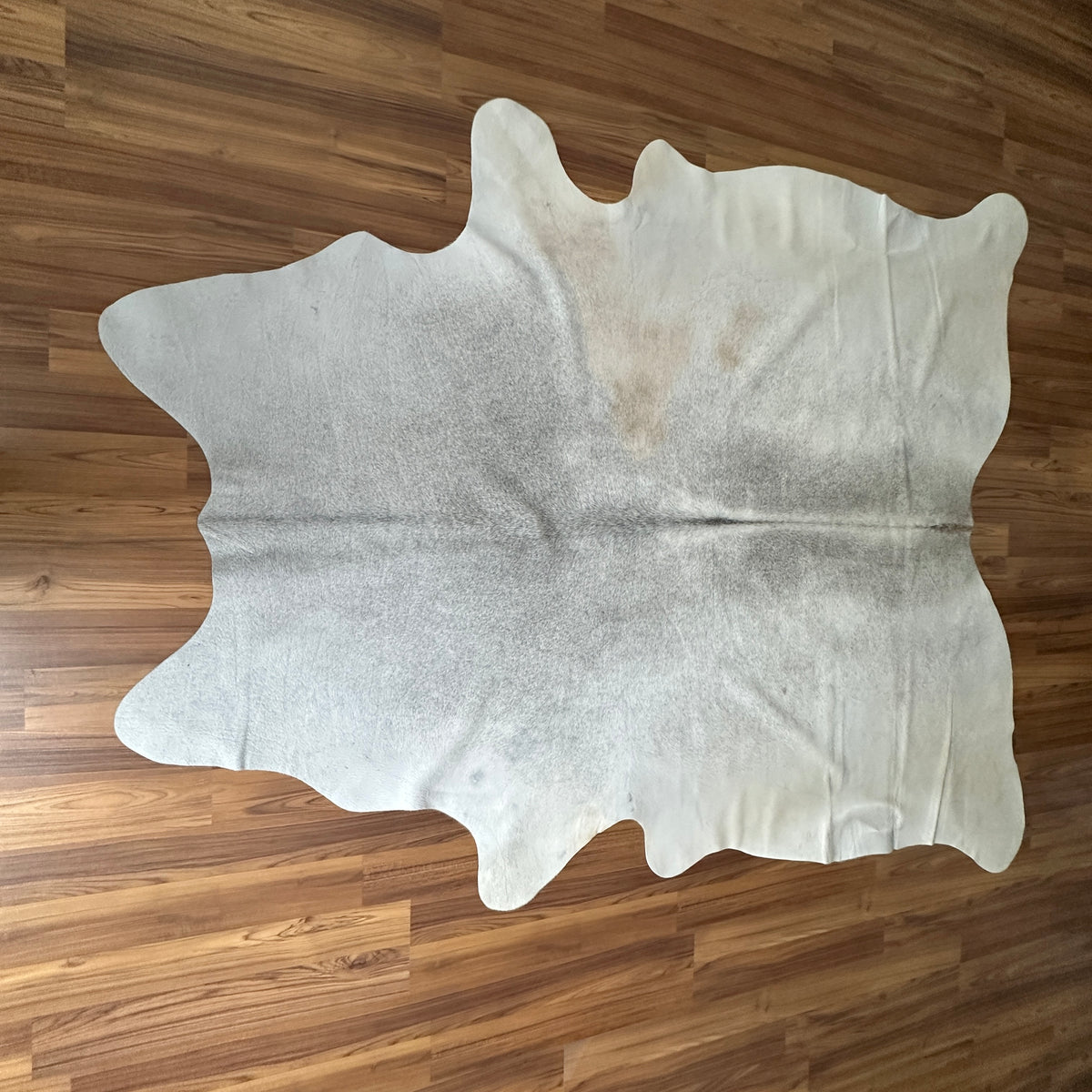 Beige cowhide rug, full overhead view — Large irregular cream and light gray patches with natural organic mottling