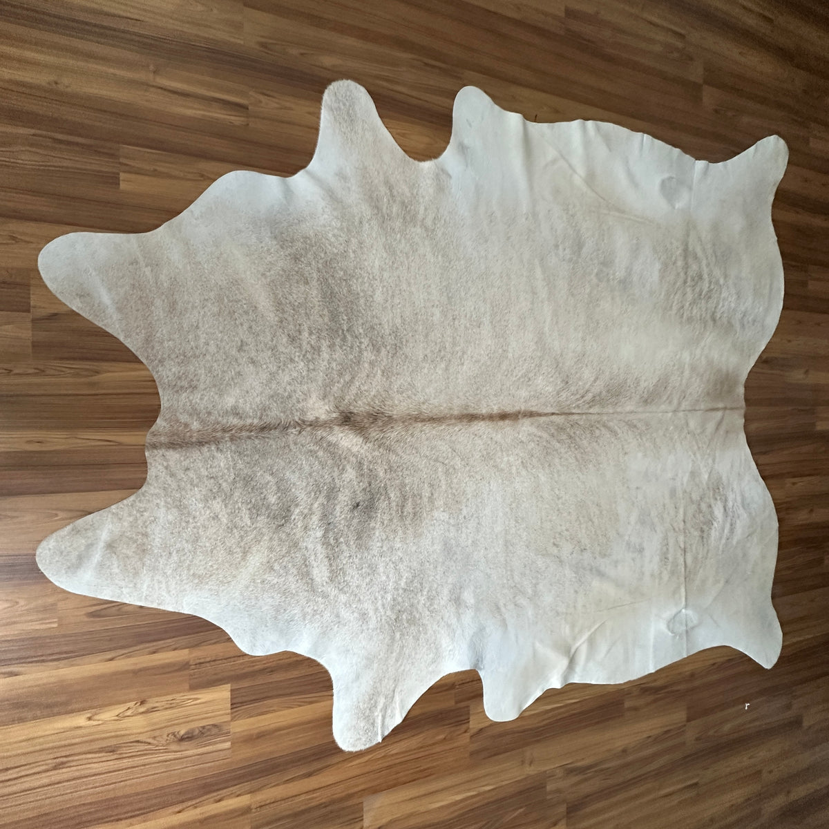 Beige cowhide rug, full overhead view — Large irregular cream and light grey patches with natural tonal variation