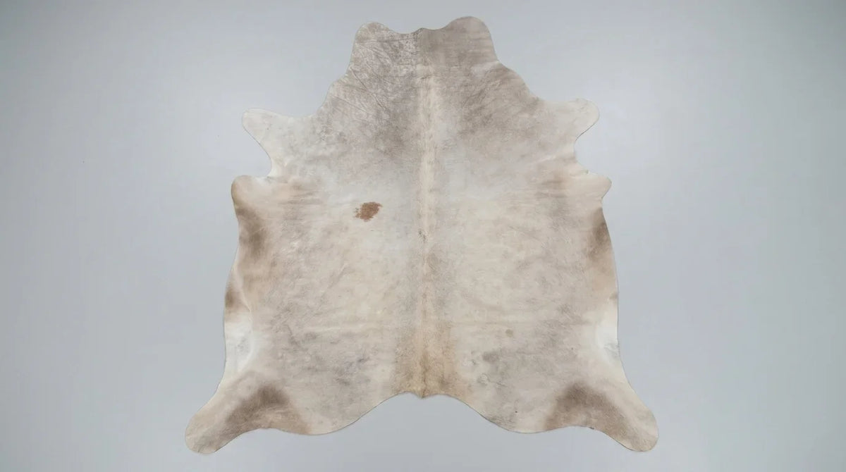 Beige cowhide rug flat lay on white background showing full hide shape