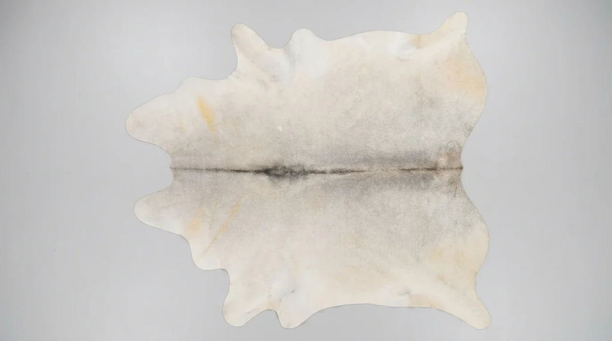 Beige cowhide rug flat lay on white background showing full hide shape