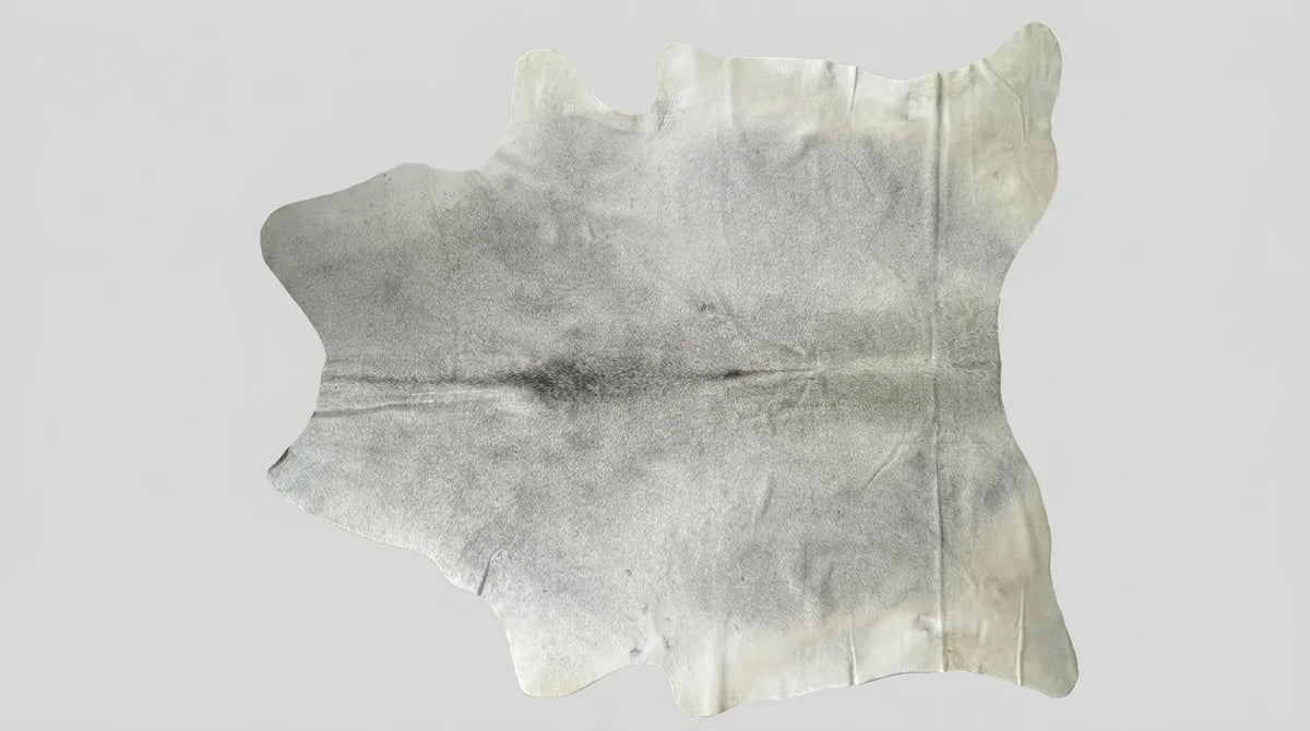 Beige cowhide rug flat lay on white background showing full hide shape