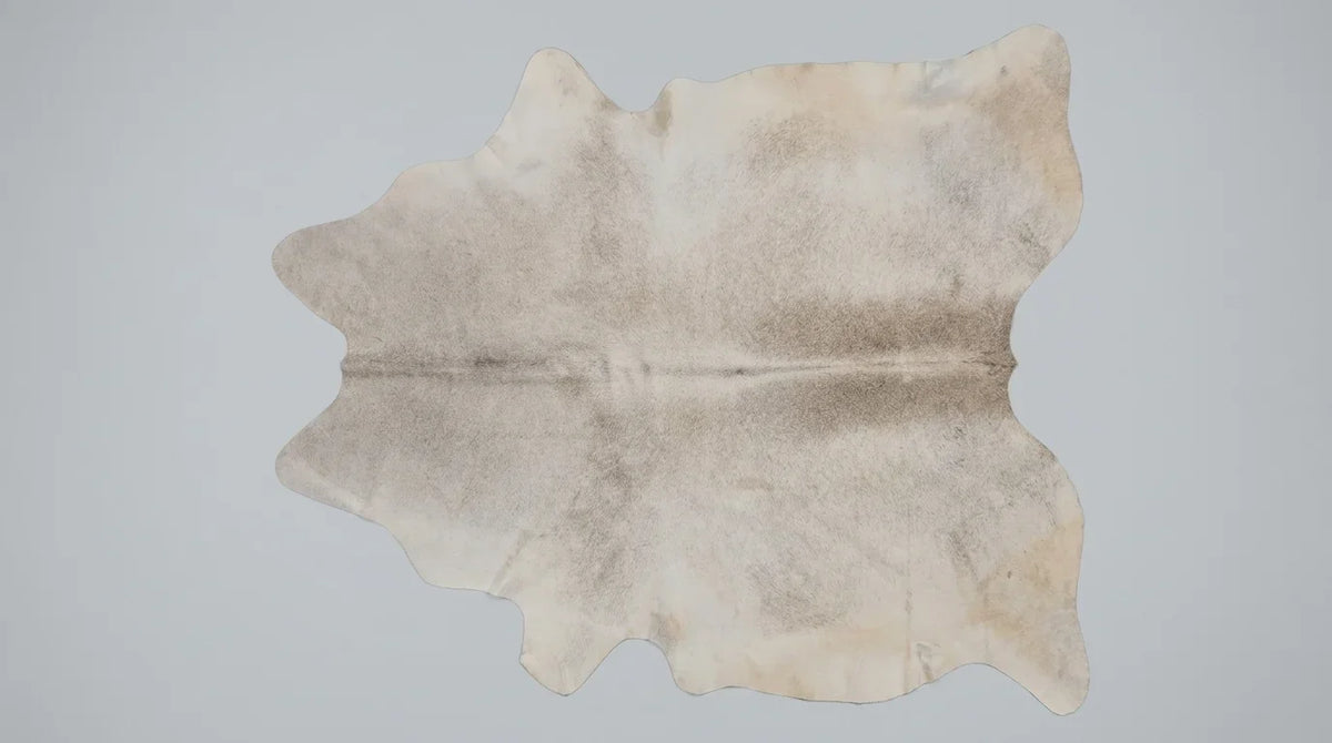 Beige cowhide rug flat lay on white background showing full hide shape