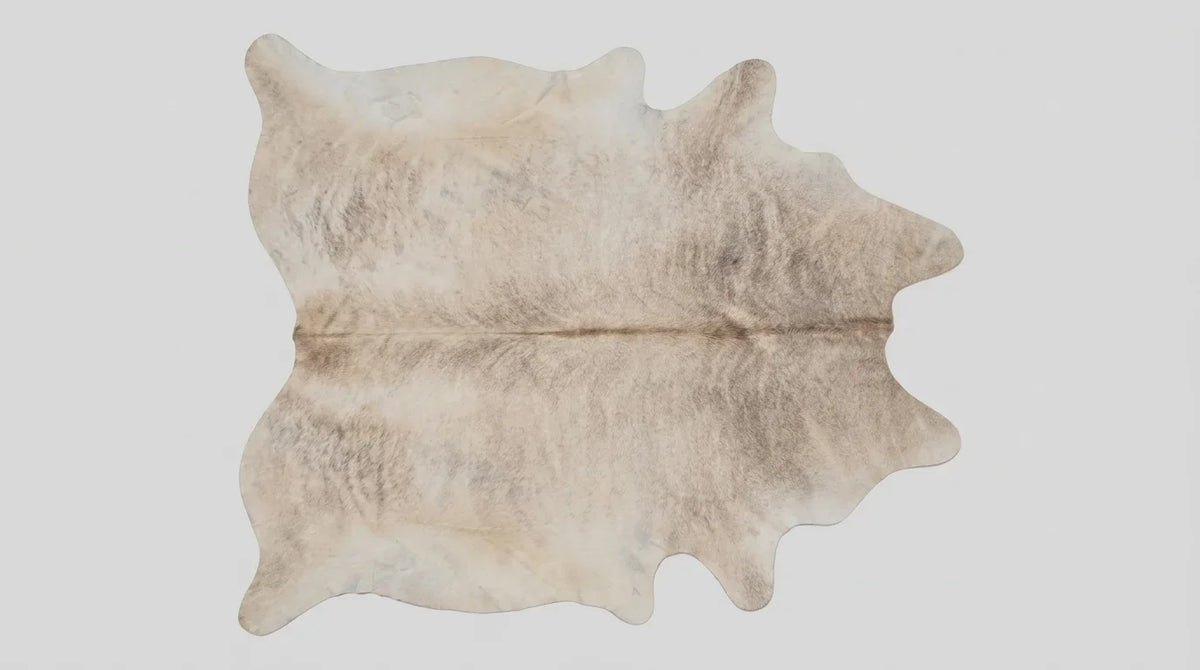 Beige cowhide rug flat lay on white background showing full hide shape
