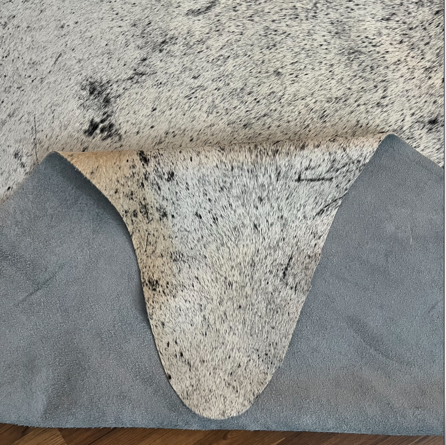 Close-up texture of Beige cowhide rug — Fine speckled texture with subtle grey and brown undertones throughout cream base