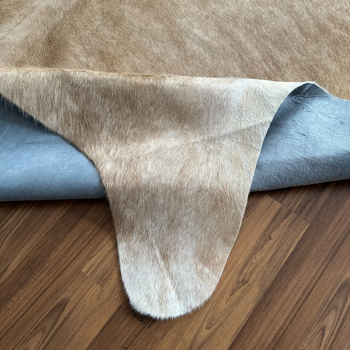 Close-up texture of Beige cowhide rug — Large irregular cream and light tan patches with natural mottled texture