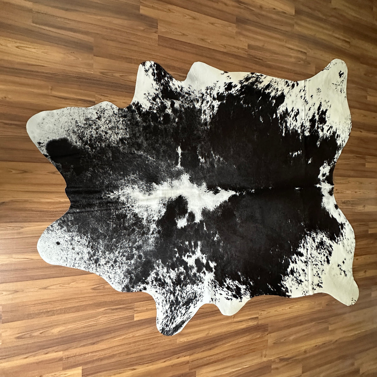 Black and White cowhide rug, full overhead view — Large irregular dark patches over cream-white base with natural spotting
