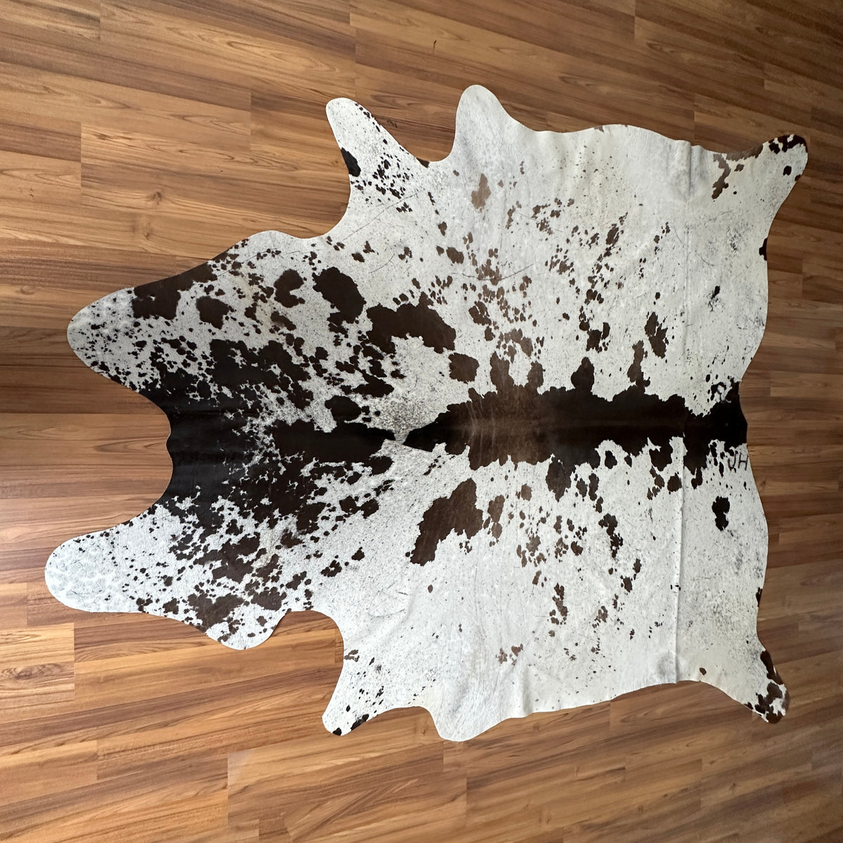 Black and White cowhide rug, full overhead view — Large irregular dark brown patches with fine speckled overlay on cream base