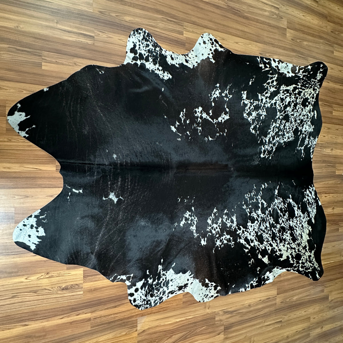 Black and White cowhide rug, full overhead view — Large irregular white patches and speckles over deep black base