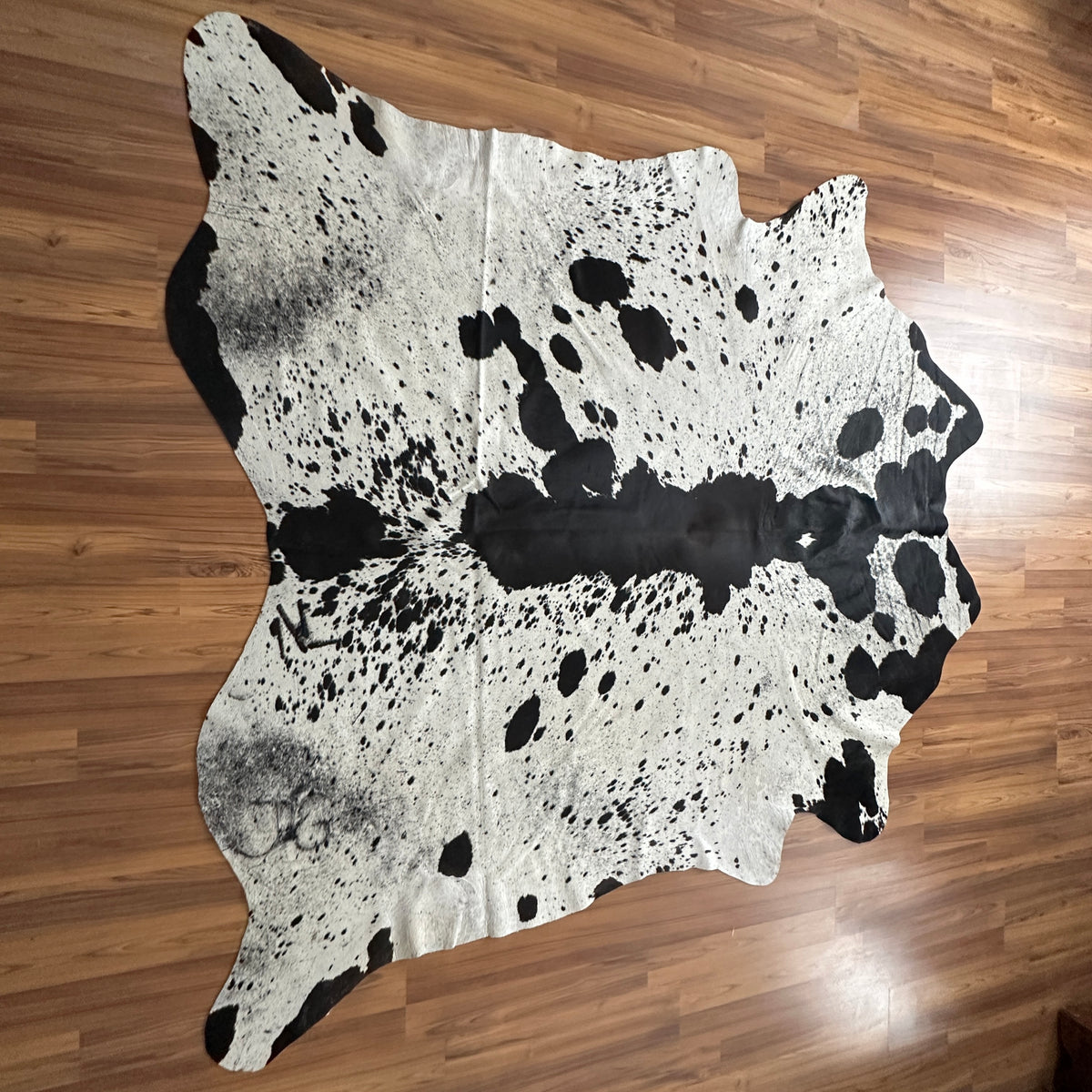 Black and White cowhide rug, full overhead view — Large irregular black patches and speckles scattered across cream and white
