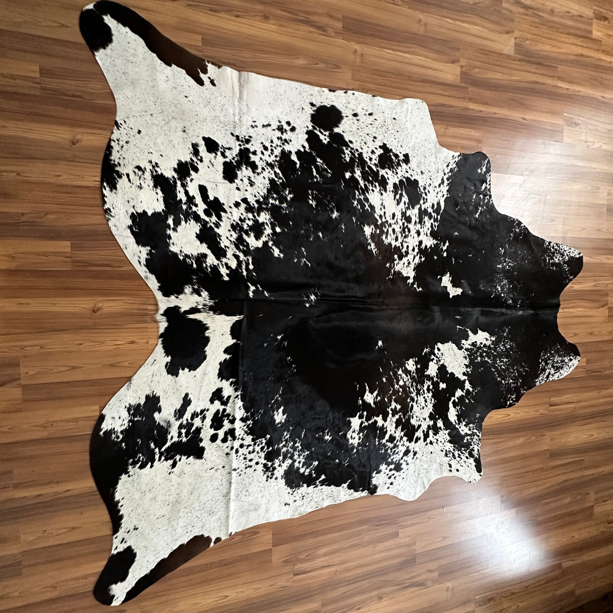 Black and White cowhide rug, full overhead view — Large irregular black patches with scattered spotting over white base