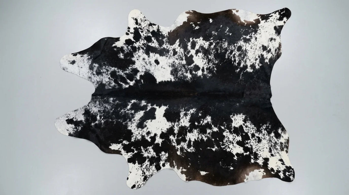 Black and White cowhide rug flat lay on white background showing full hide shape