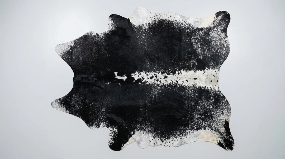 Black and White cowhide rug flat lay on white background showing full hide shape
