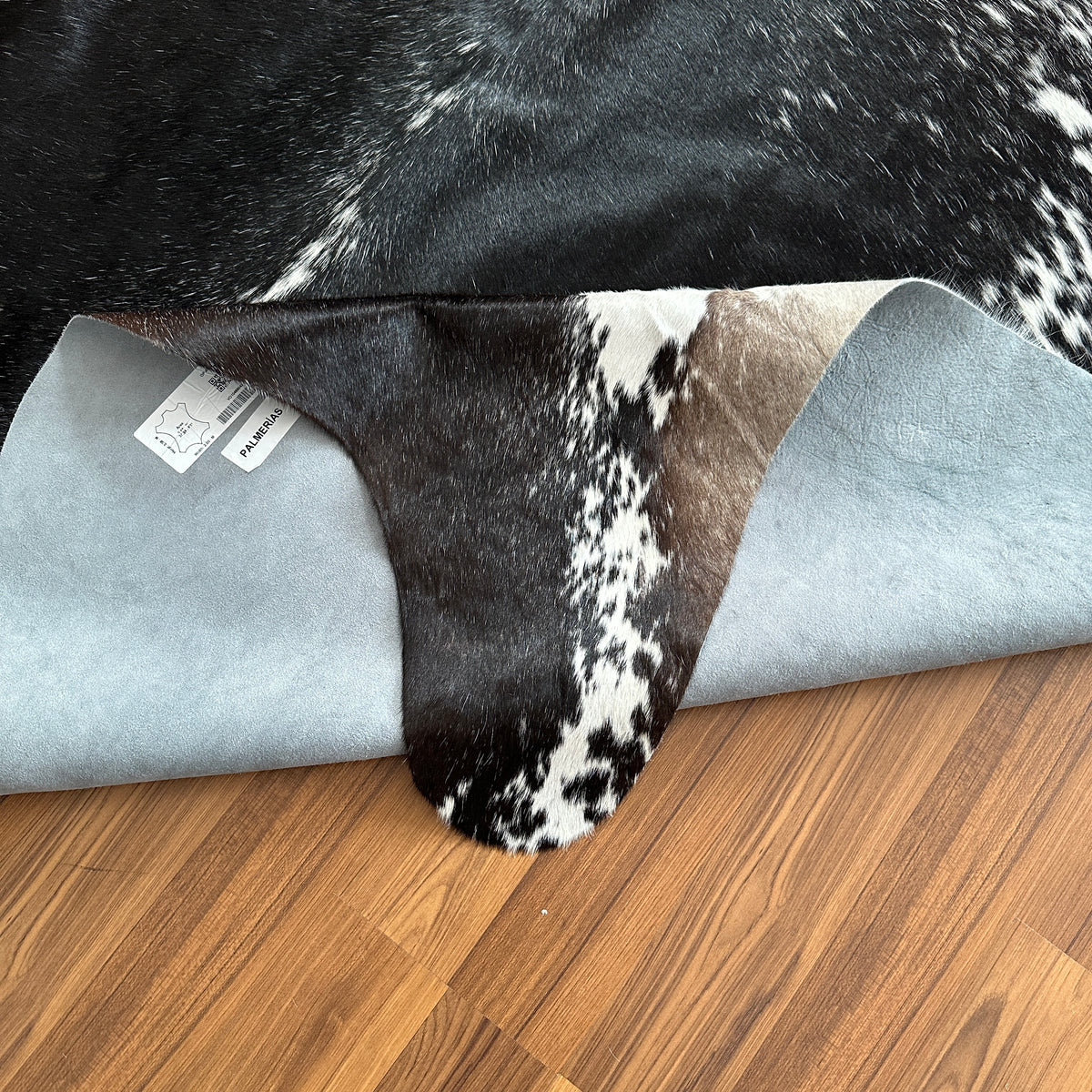 Close-up texture of Black and White cowhide rug — Large irregular black patches with white speckled markings over cream base