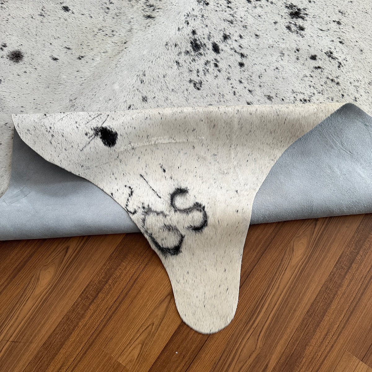 Close-up texture of Black and White cowhide rug — Large irregular dark brown and black patches scattered across cream and whi