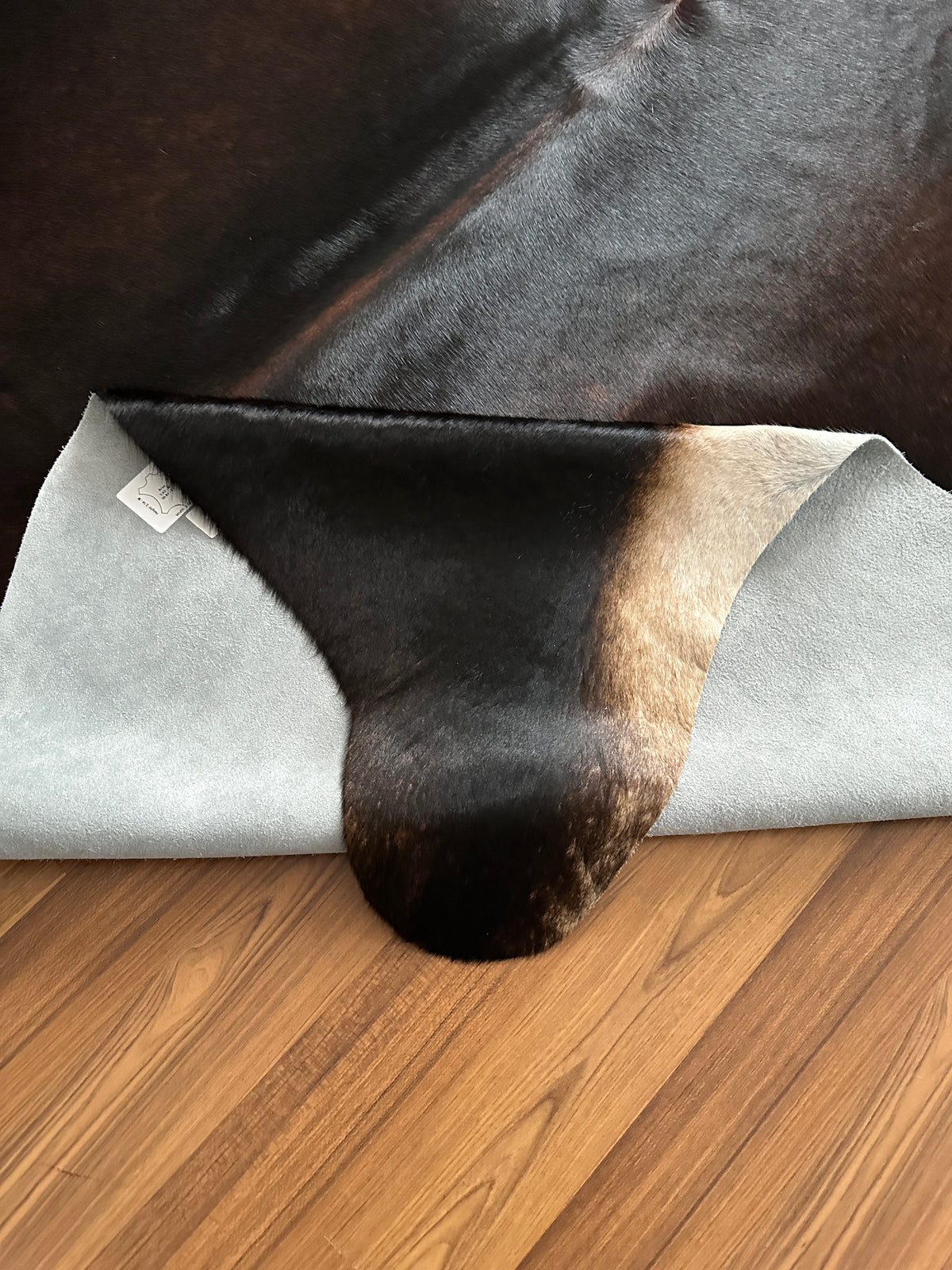 Close-up texture of Black and White cowhide rug — Large irregular dark brown-black patches with cream and tan undertones over