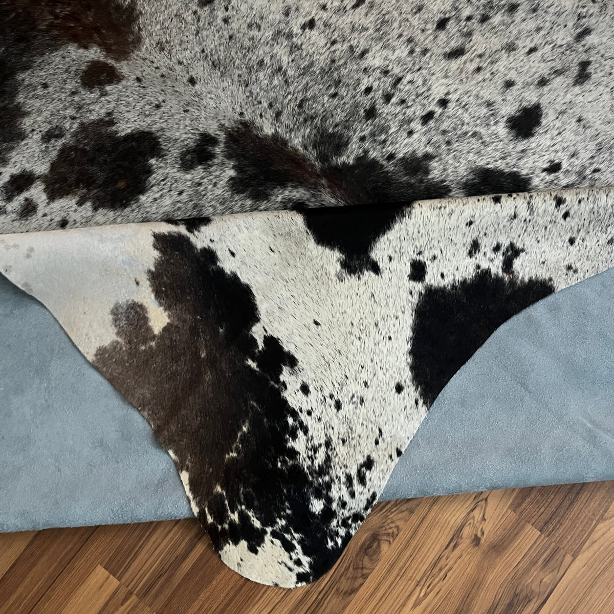 Close-up texture of Black and White cowhide rug — Large irregular black patches and speckles over white cream base