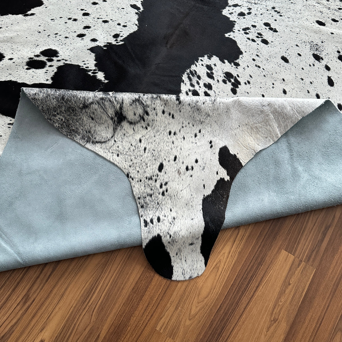 Close-up texture of Black and White cowhide rug — Large irregular black patches and speckles scattered across cream and white