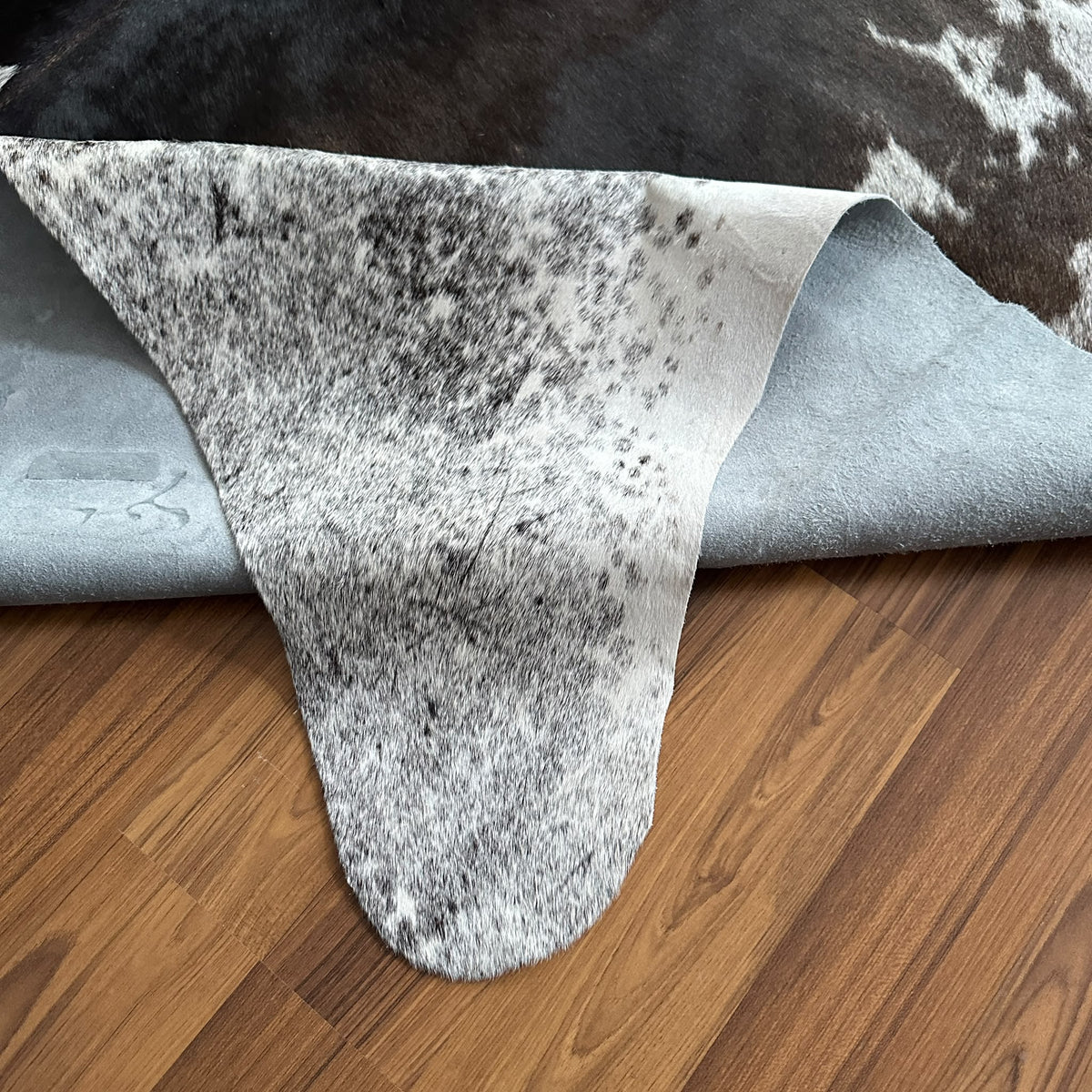 Close-up texture of Black and White cowhide rug — Large irregular dark brown and black patches over cream and white base