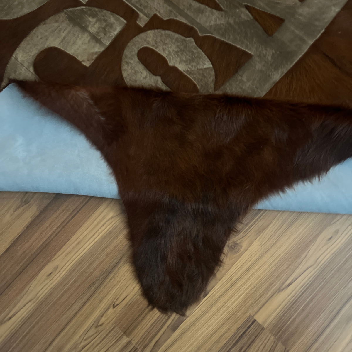 Close-up texture of Black and White exotic cowhide rug — Large embossed cowboy boot and hat motif on dark brown-black base wi