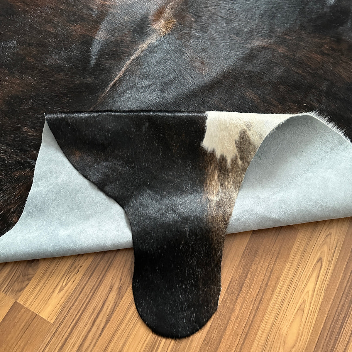 Close-up texture of Black and White cowhide rug — Large irregular black patches with white markings on face, legs, and unders