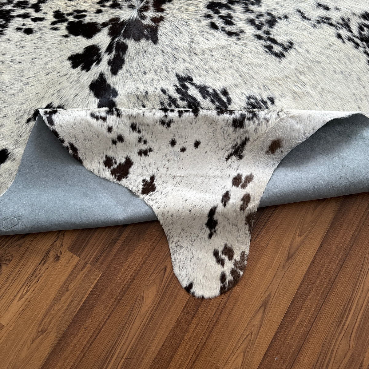 Close-up texture of Black and White cowhide rug — Large irregular black patches over white cream base with fine speckled mark