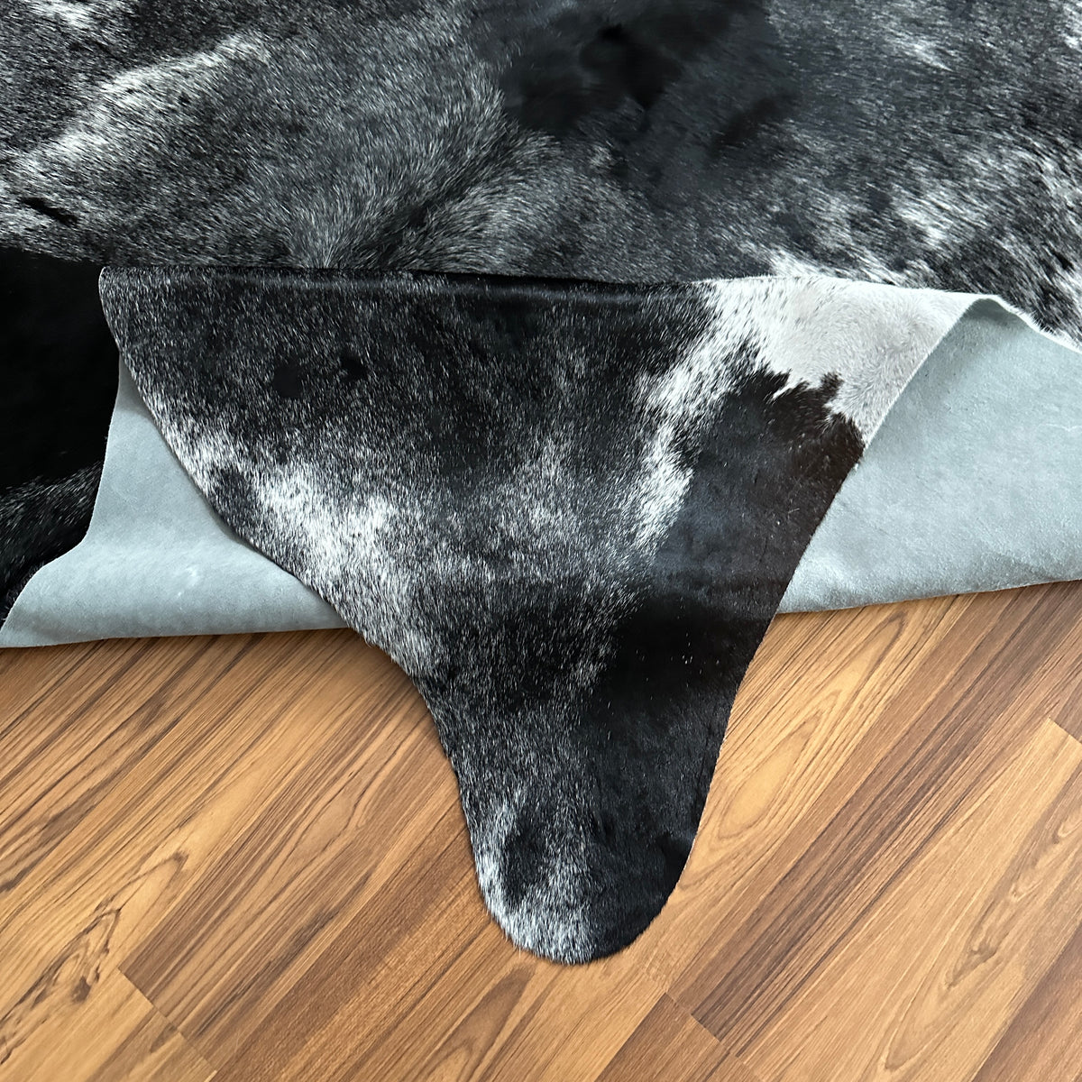 Close-up texture of Black and White cowhide rug — Large irregular black patches and speckles over white base with natural hid